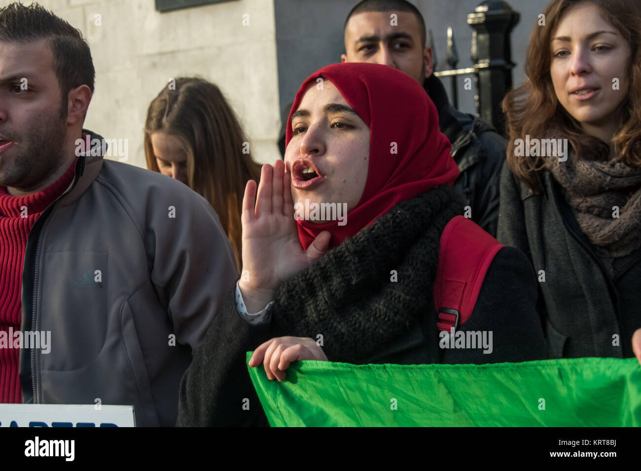 Una donna in un velo rosso grida "Cibo non bombe" in segno di protesta per la Siria in Trafalgar Square. Foto Stock
