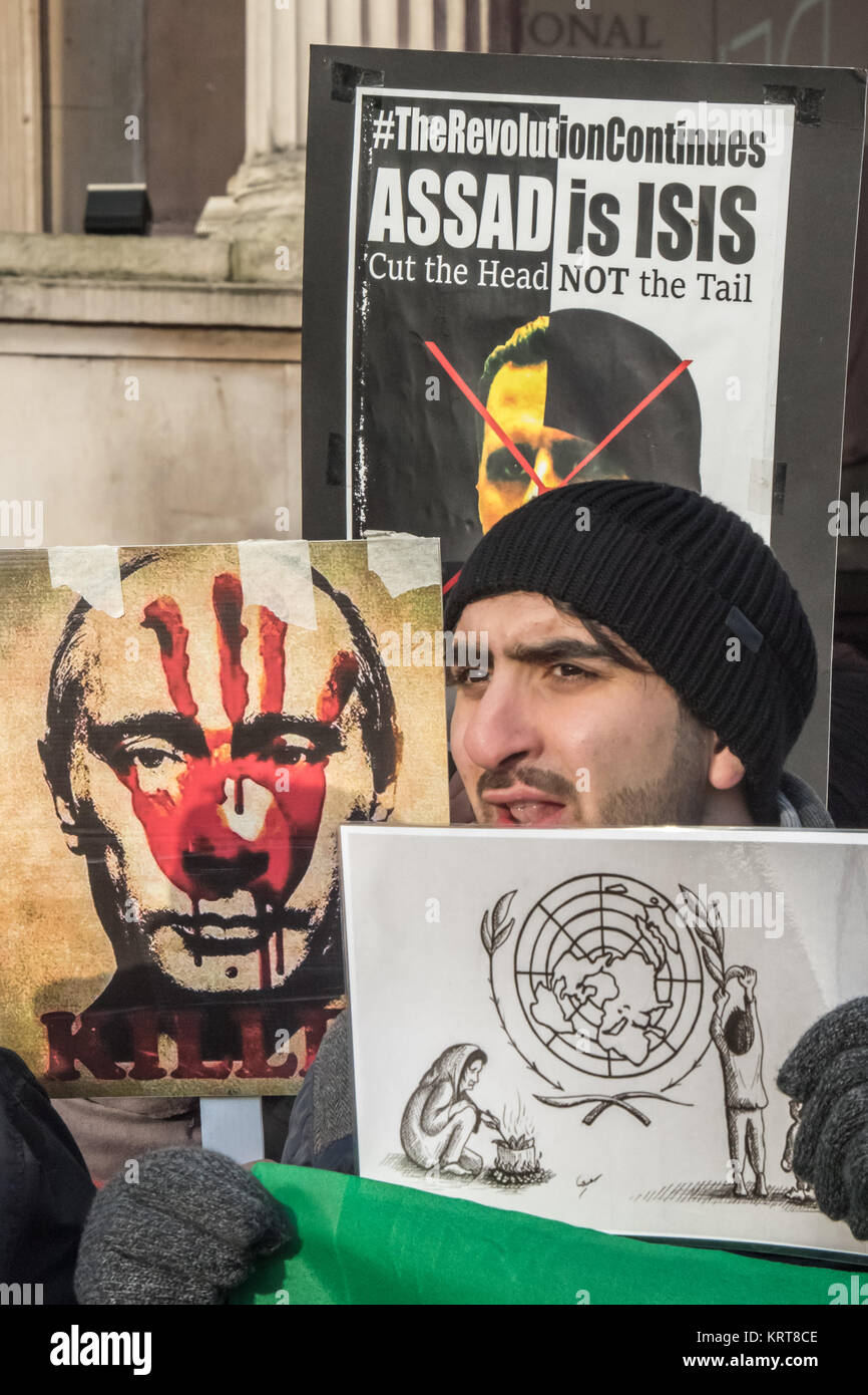 Putin, Assad e un passamontagna ISIS su manifesti dietro un manifestante tenendo un cartone animato che mostra un giovane siriano cucinare le foglie dal logo DELLE NAZIONI UNITE presso la "Cibo non bombe' protestare per la Siria in Trafalgar Square. Foto Stock