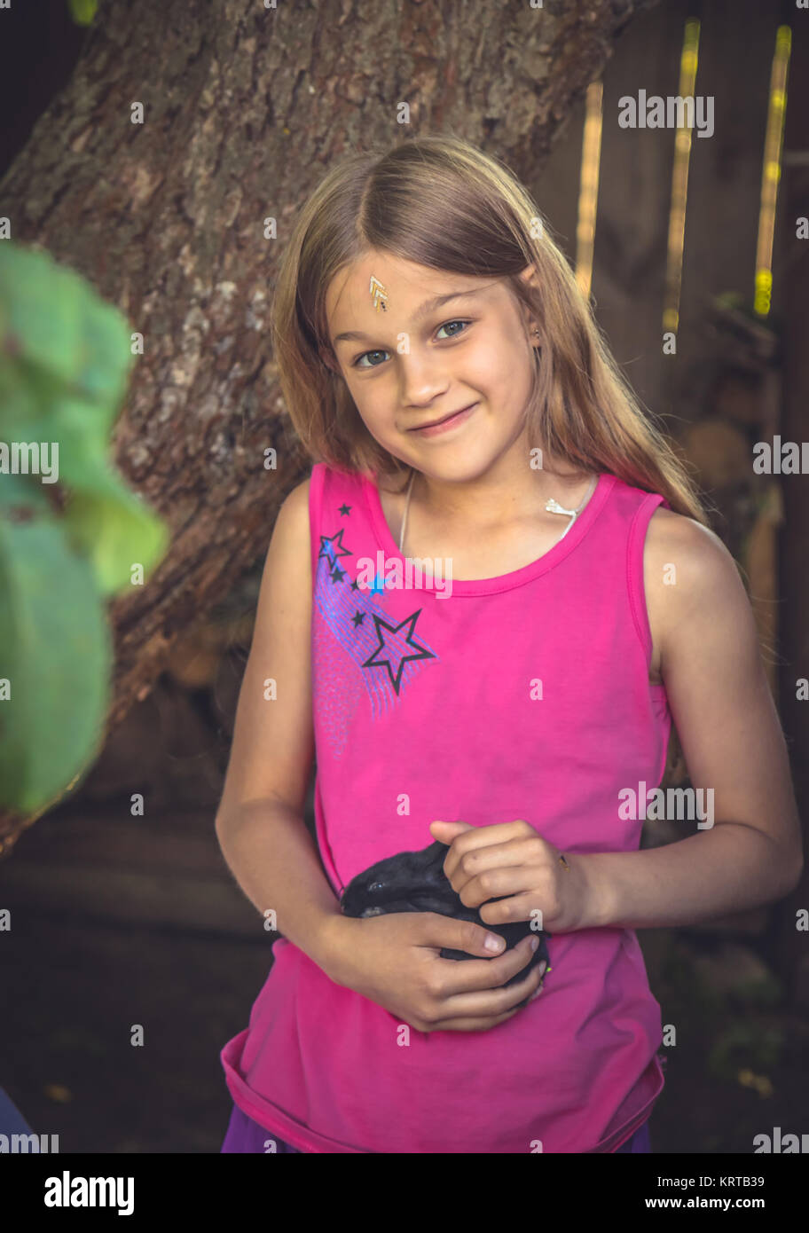 Bellissimo bambino sorridente ragazza carezza coniglio in campagna che simboleggiano cura degli animali Foto Stock