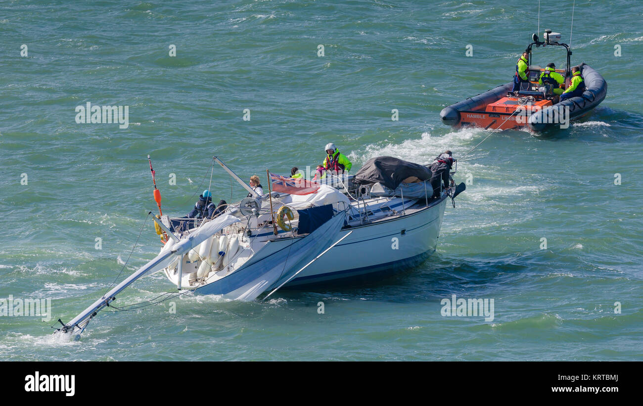 Il RNLI trainare un dismasted yacht durante il giro dell'isola di gara. Isola di Wight. Picture Data: Sabato 2 Luglio 2, 2016. Fotografia da Christopher Ison © Foto Stock