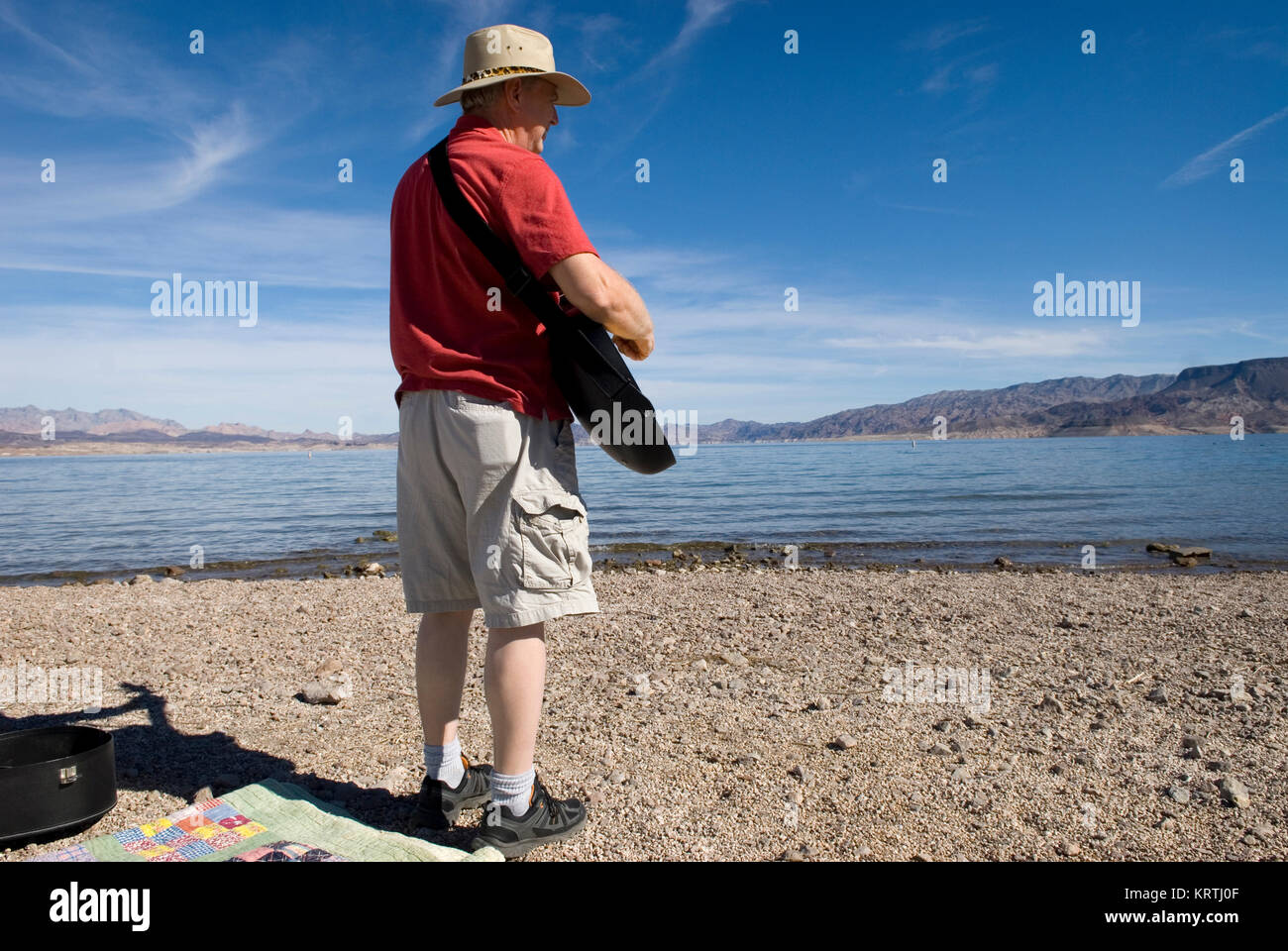 Uomo suona la chitarra sulla spiaggia al lago Mead National Recreation Area Nevada, USA. Foto Stock