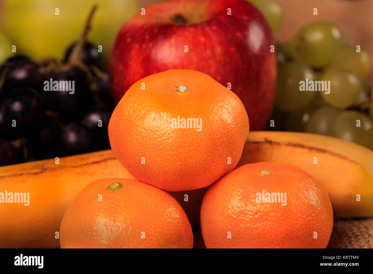 Nutrizione organica frutto sano cibo. Mandarino, Apple con i colori giallo e blu uva e banana Foto Stock