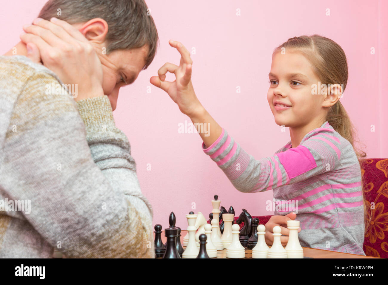 Mia figlia ha un dito sul Papa's head, che ha perso una partita a scacchi Foto Stock