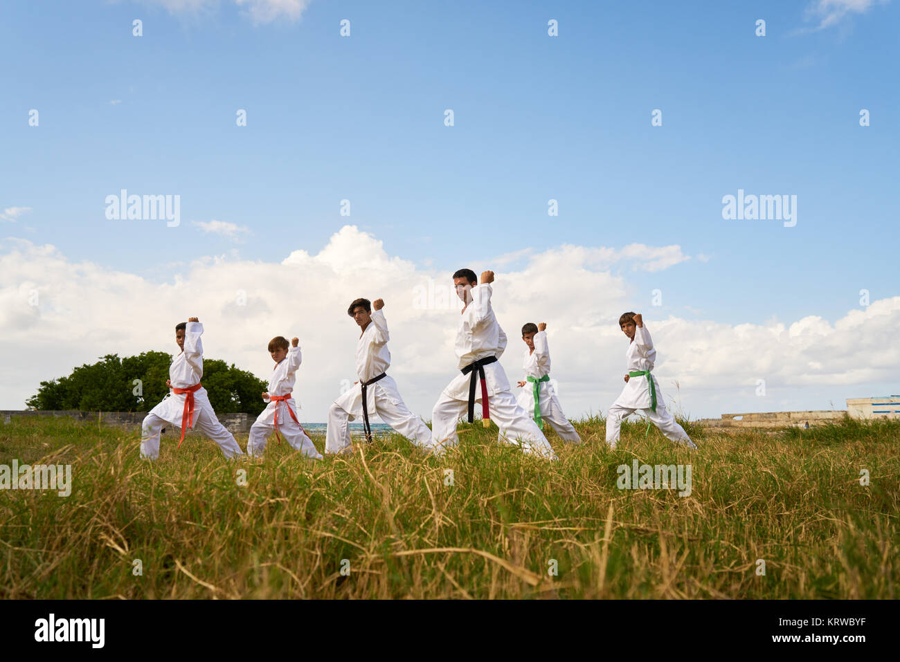 Ispanico agli uomini e ai bambini che esercitano nel karate tradizionale e arti marziali. Simulazione di lotta sulla spiaggia vicino al mare Foto Stock