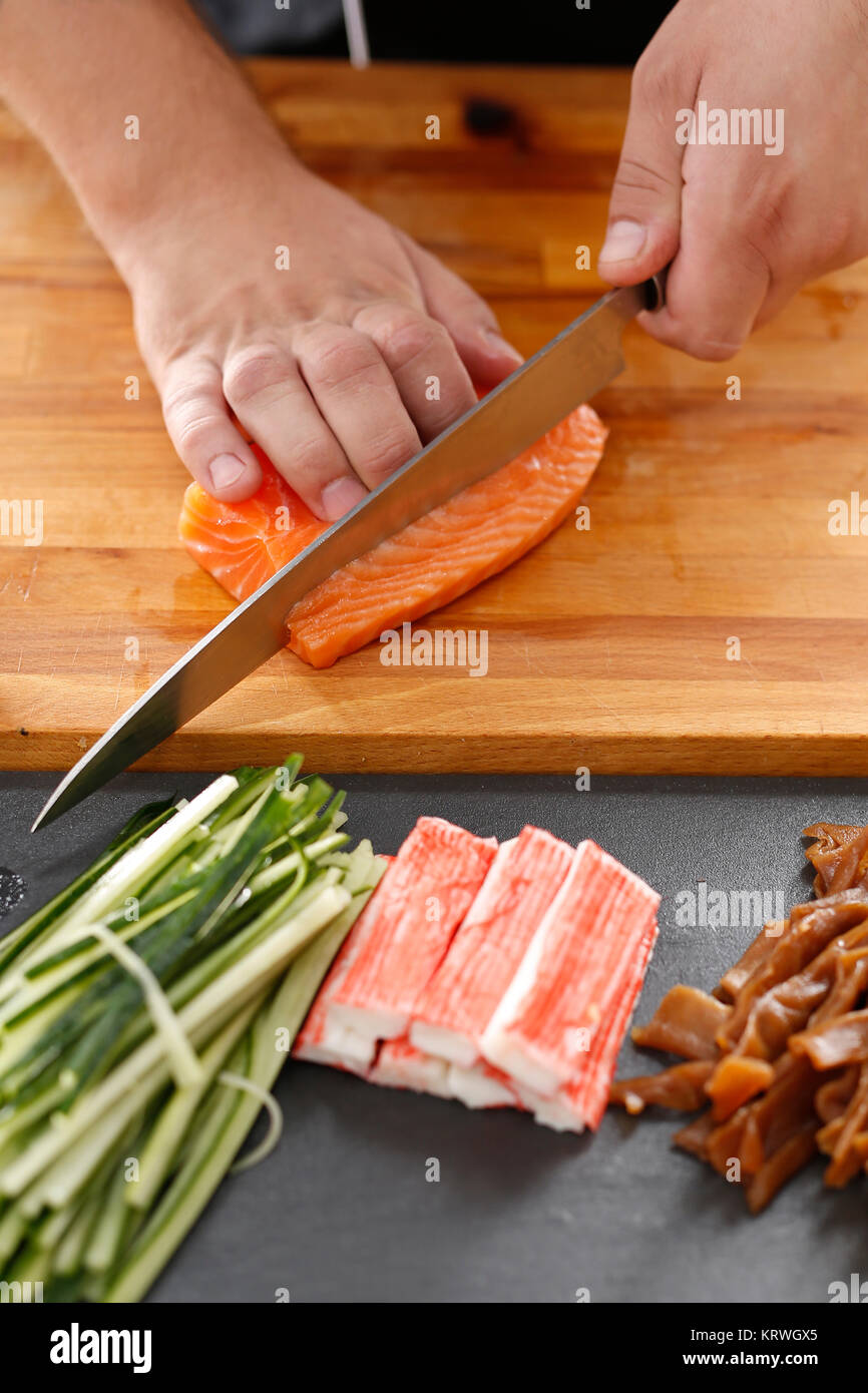 Sushi , etapy przygotowywania sushi z Å'ososiem, paluszkiem krabowym, ogÃ³rkiem tykwÄ… zawiniÄ™tego w glon nori Foto Stock