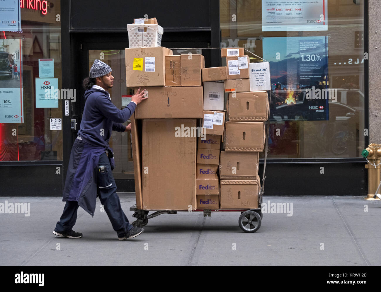 Una consegna Fedex uomo offre decine di scatole di un edificio per uffici su Broadway vicino Herald Square a Manhattan. Foto Stock