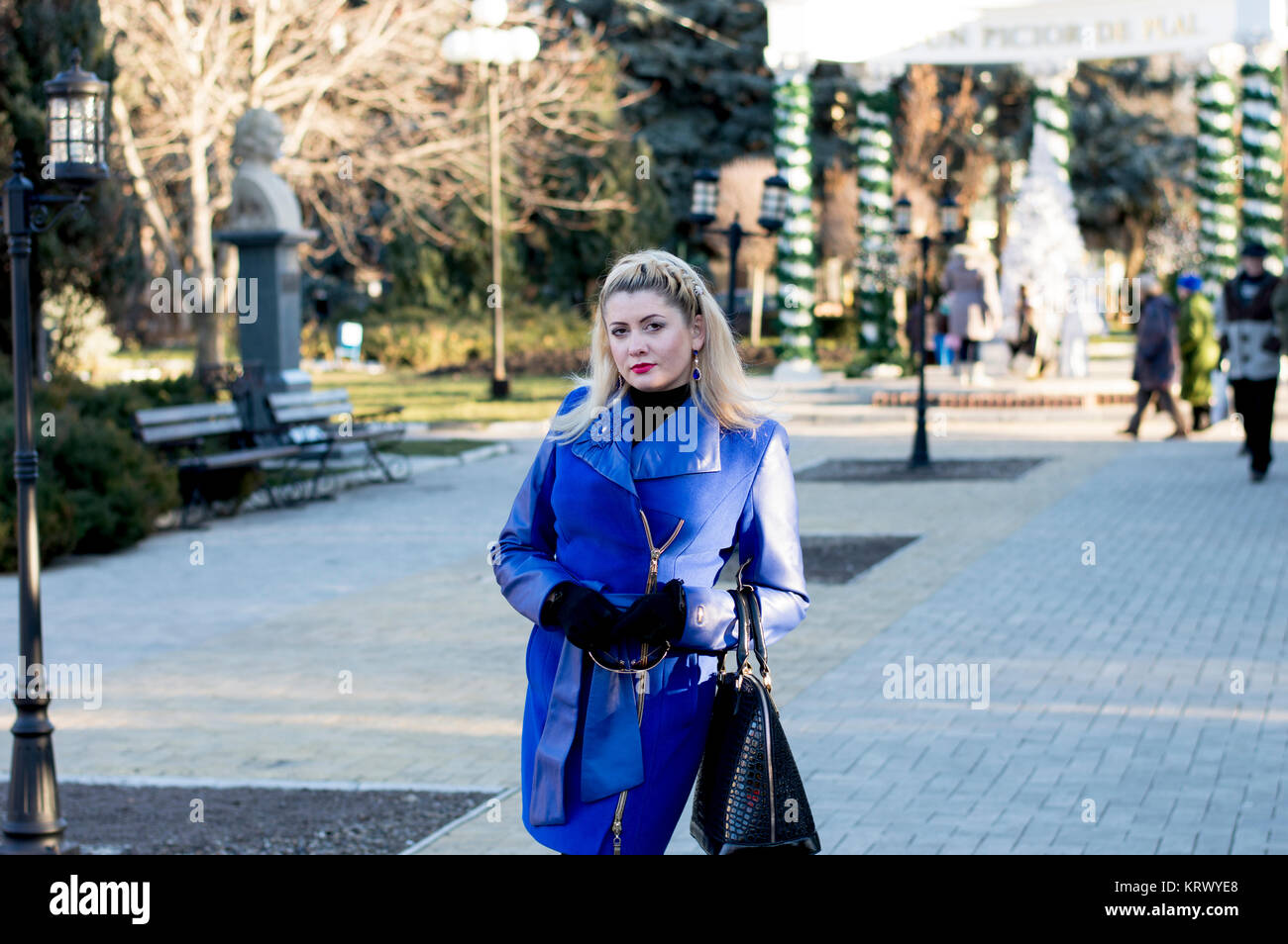 La bella donna di un mantello blu passeggiate sulla città di inverno Foto Stock