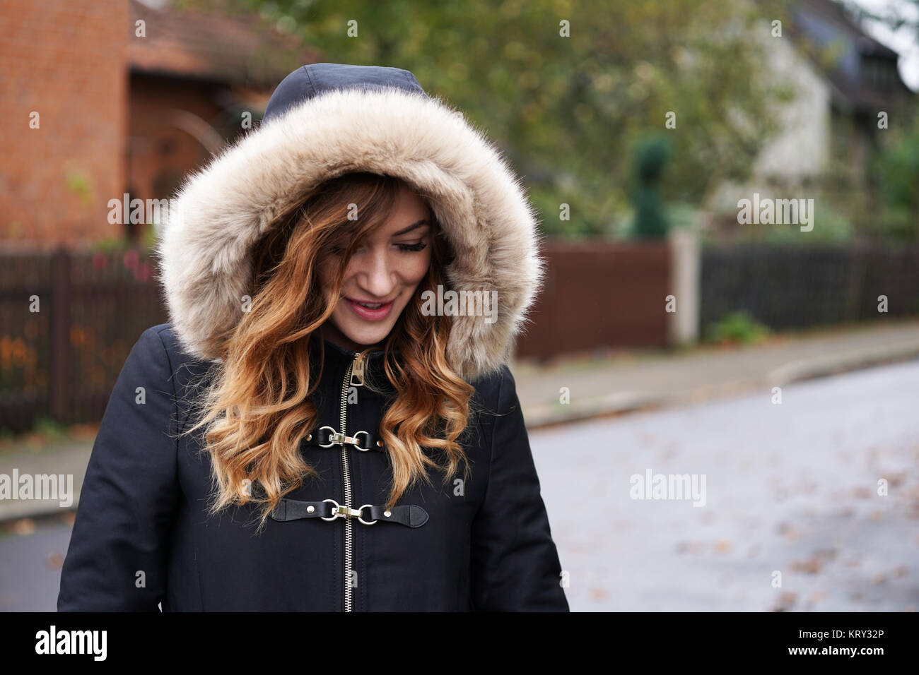 Giovane donna che indossa con cappuccio cappotto invernale giocando coy Foto Stock