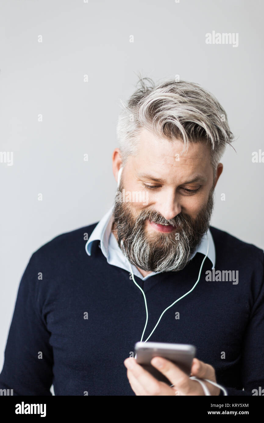 Un uomo con auricolari in ascolto per il suo telefono cellulare Foto Stock