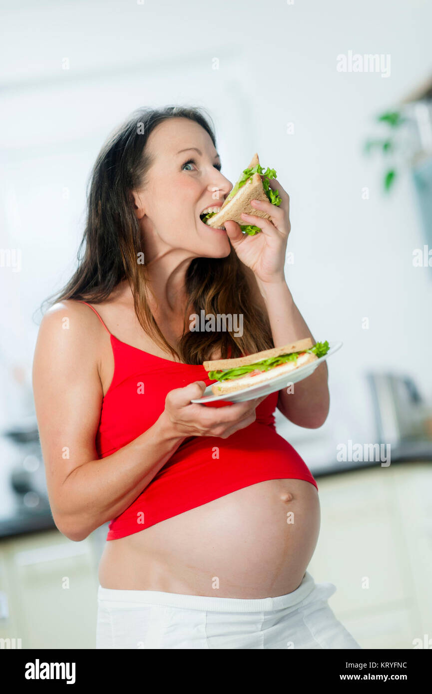 Schwangere Frau isst ein panino - donna incinta mangia un sandwich Foto Stock