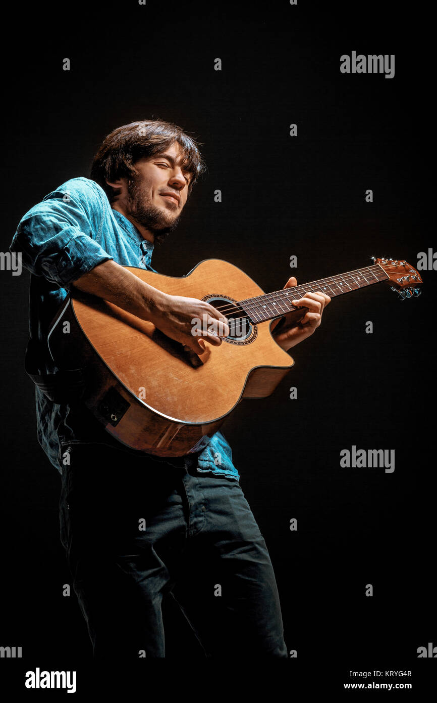 Cool guy standing con la chitarra su sfondo scuro Foto Stock