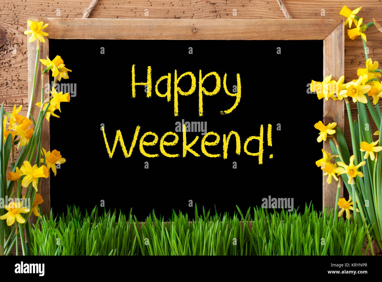 Lavagna con testo in inglese Happy Weekend. Fiori di Primavera Nacissus o Daffodil con erba. Rustico in legno invecchiato sfondo. Foto Stock