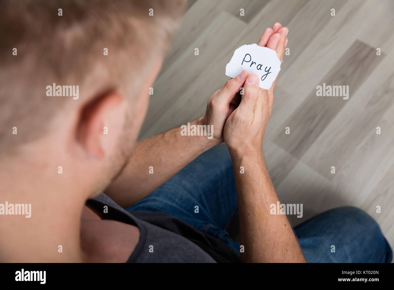 Pezzo di carta con testo di pregare in mano d'uomo Foto Stock