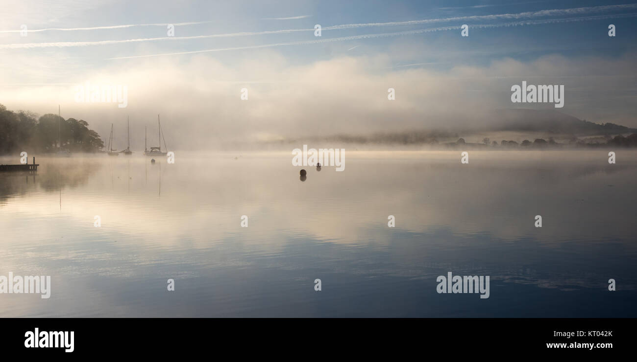 La nebbia sorge intorno alle barche ormeggiate sul lago di Windermere a Ambleside in Inghilterra del Parco Nazionale del Distretto dei Laghi. Foto Stock