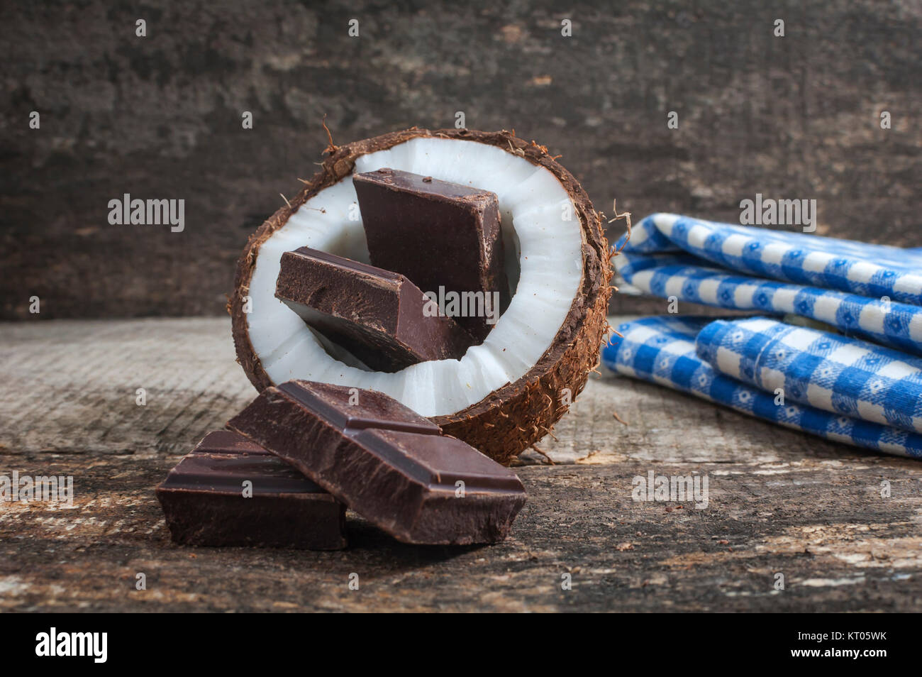 Noce di cocco con cioccolato sulla vecchia sullo sfondo di legno Foto Stock