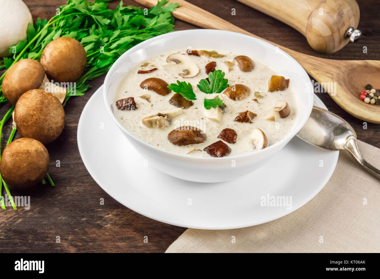 Una foto di una piastra di un fungo minestra in crema con champignon, cremini, prezzemolo fresco e pepe, al buio su un rustico texture di sfondo con un posto per Foto Stock