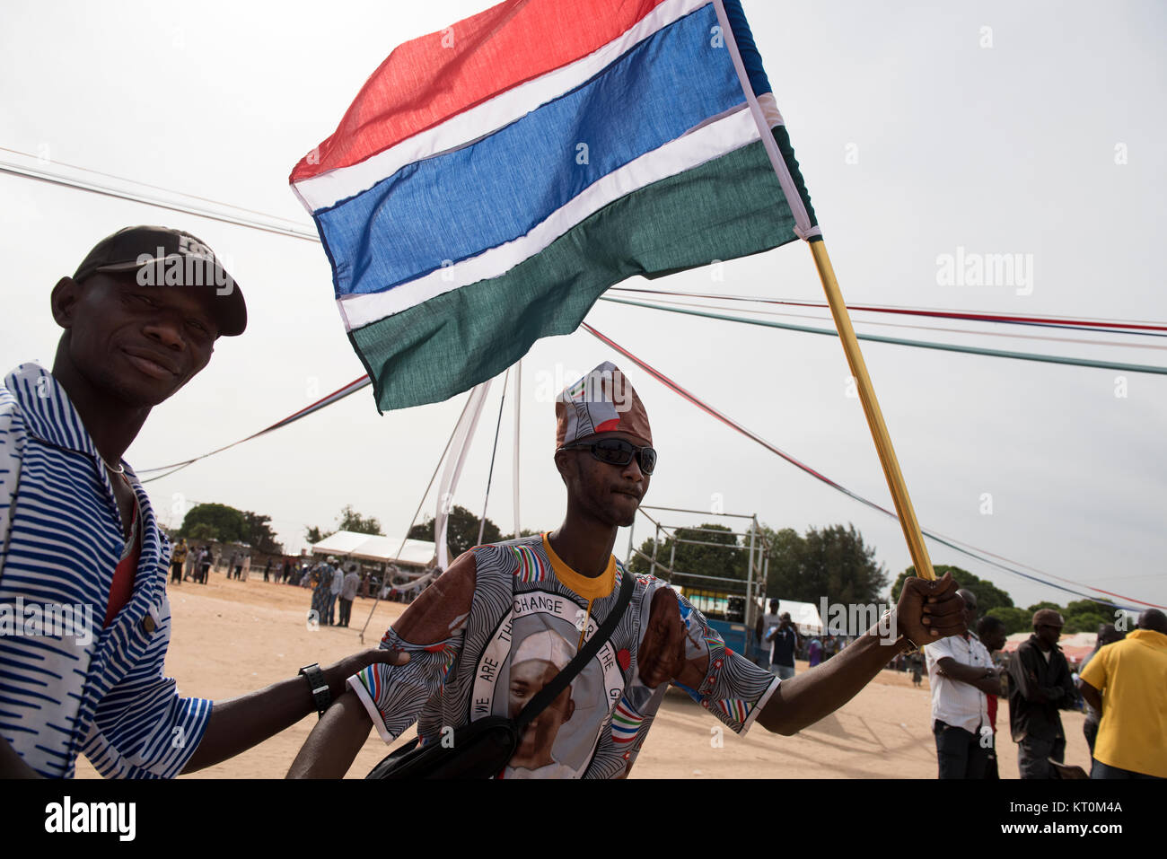 Giovane uomo è indossano i vestiti che rappresentano il presidente del Gambia Adama Barrow, sventolando nazionale bandiera del Gambia Foto Stock