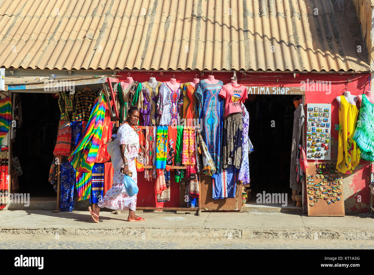 Donna locale camminare davanti a un negozio di souvenir, Santa Maria, Isola di Sal, Salina, Capo Verde, Africa Foto Stock