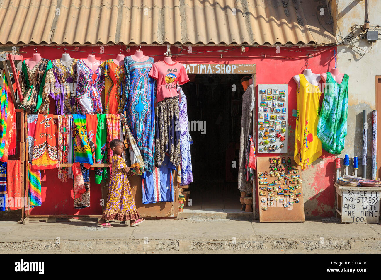 Ragazza locale oltrepassando un souvenir negozio di abbigliamento, Santa Maria, Isola di Sal, Salina, Capo Verde, Africa Foto Stock