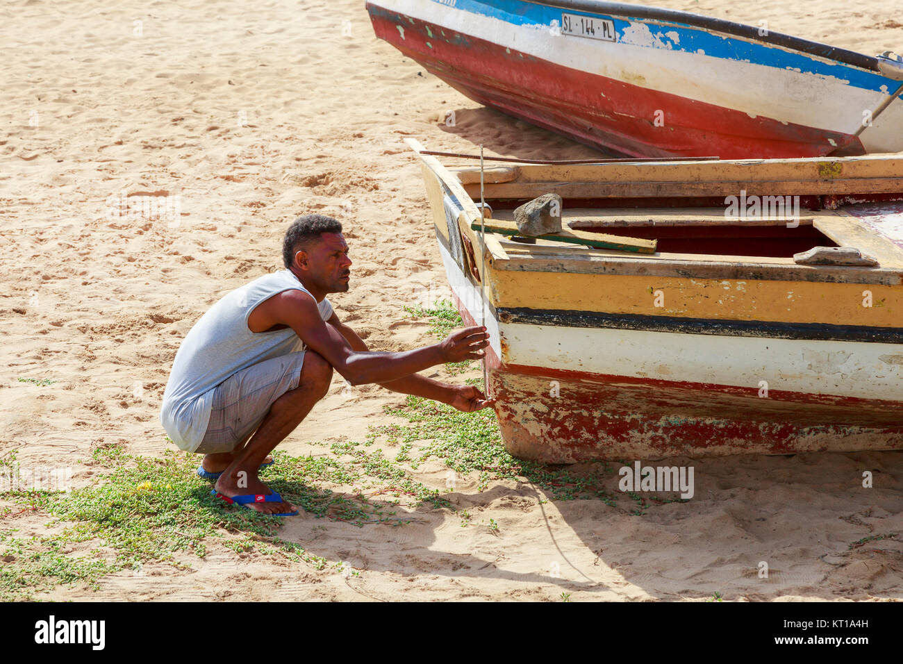 Pescatore locale riparando il suo legno barca da pesca sulla spiaggia di Santa Maria, Isola di Sal, Salina, Capo Verde, Africa Foto Stock