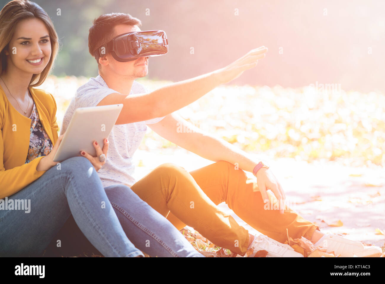 Giovane seduto fuori utilizzando vari tech gadgets, tablet, vr, concept Foto Stock