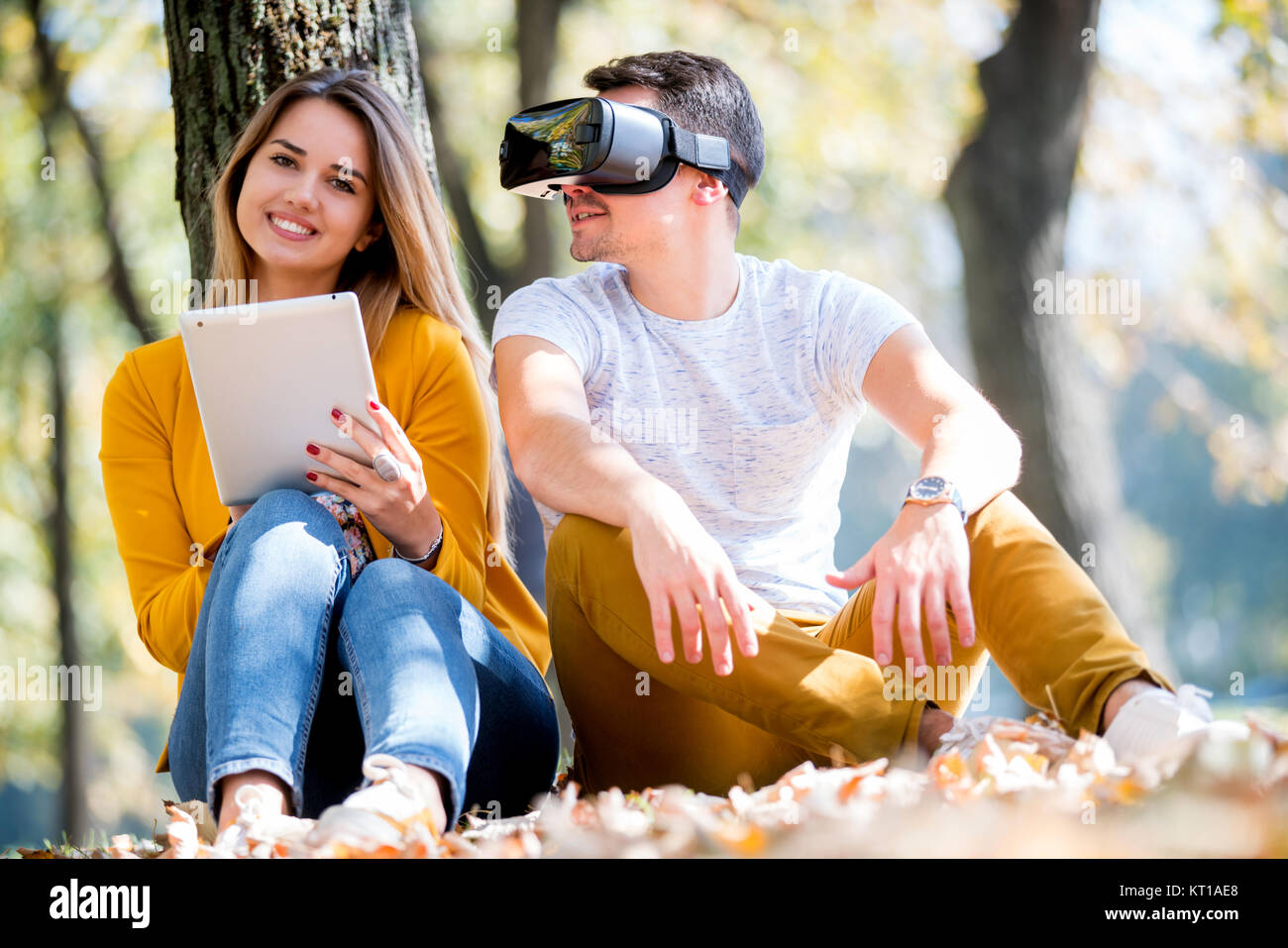 Giovane seduto fuori utilizzando vari tech gadgets, tablet, vr, concept Foto Stock