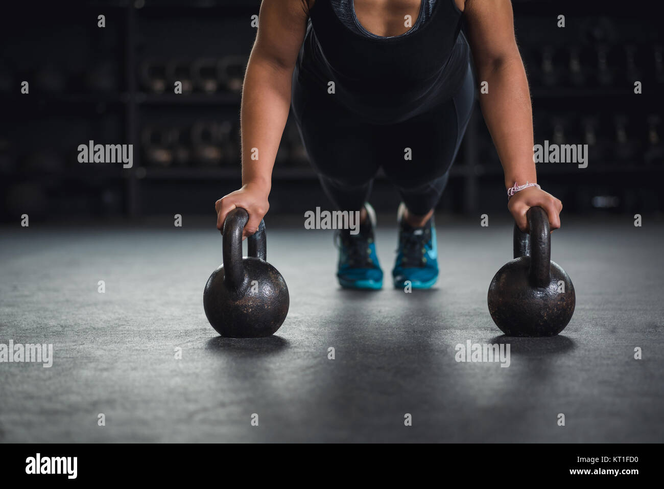 Donna etnica lavorando in palestra con kettlebells. Foto Stock