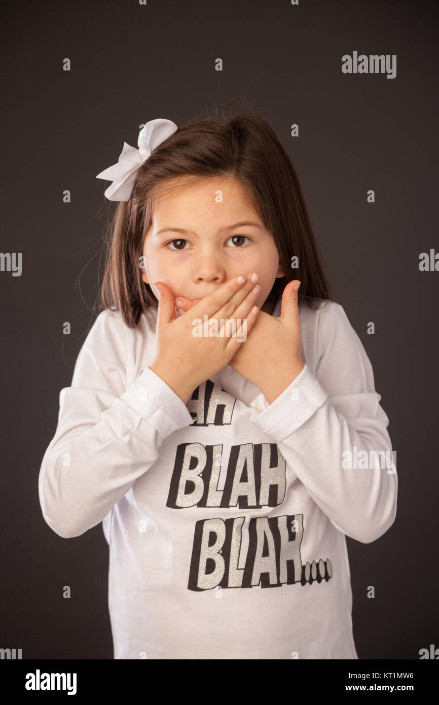 7 anno vecchia ragazza cercando sorpreso con la sua mano sopra la sua bocca. Foto Stock