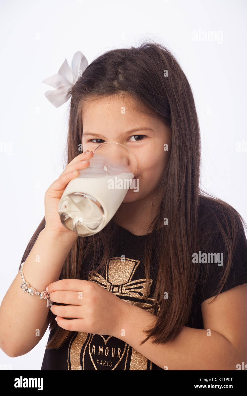 A sette anni di ragazza di bere un bicchiere di latte. Foto Stock