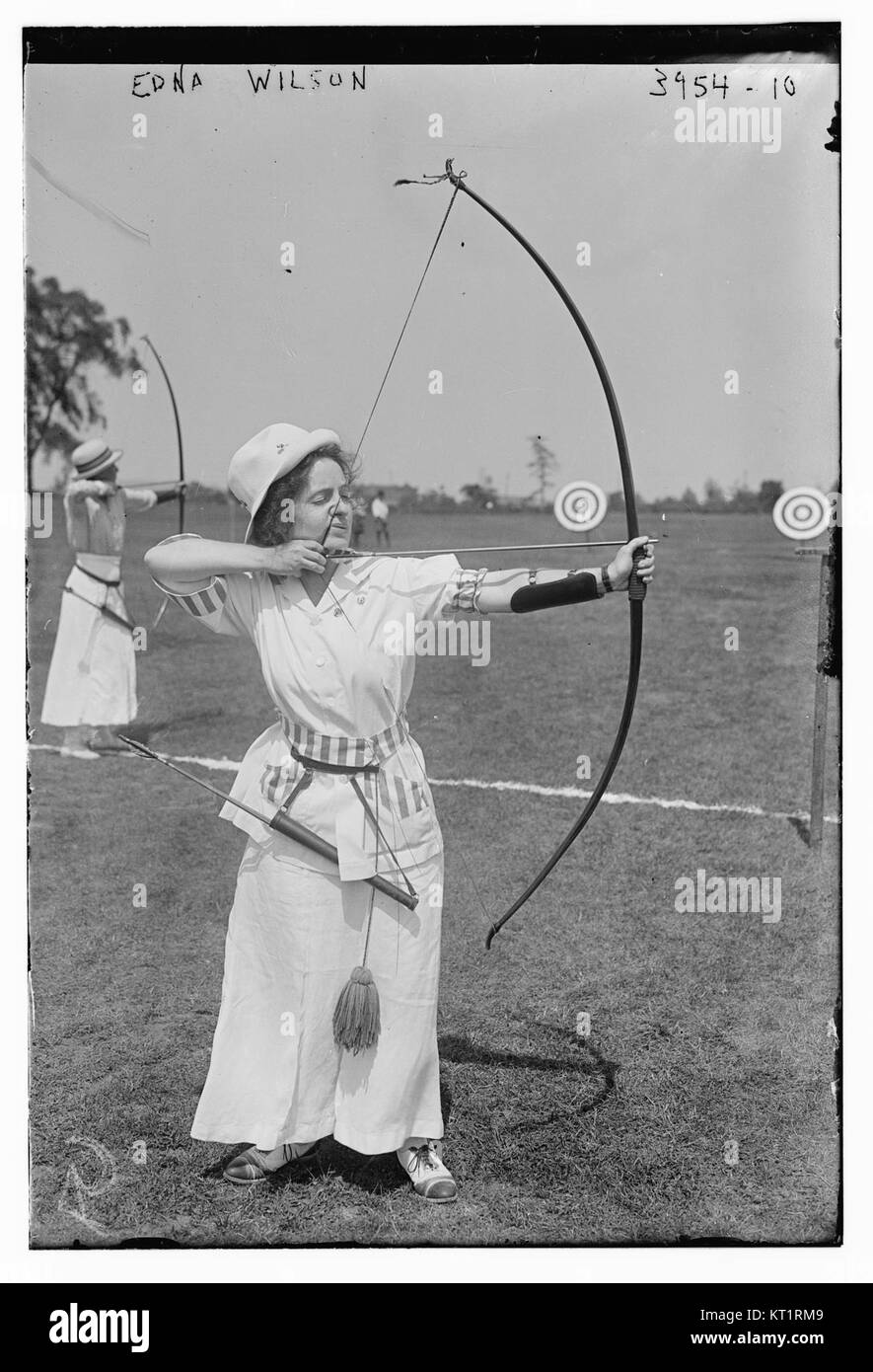 La fotografia mostra Edna Wilson che tiene in mano un arco e una freccia, probabilmente catturati durante un evento o una pratica di tiro con l'arco. Edna è probabilmente nota per le sue abilità nel tiro con l'arco o per la sua partecipazione ad attività correlate. Foto Stock