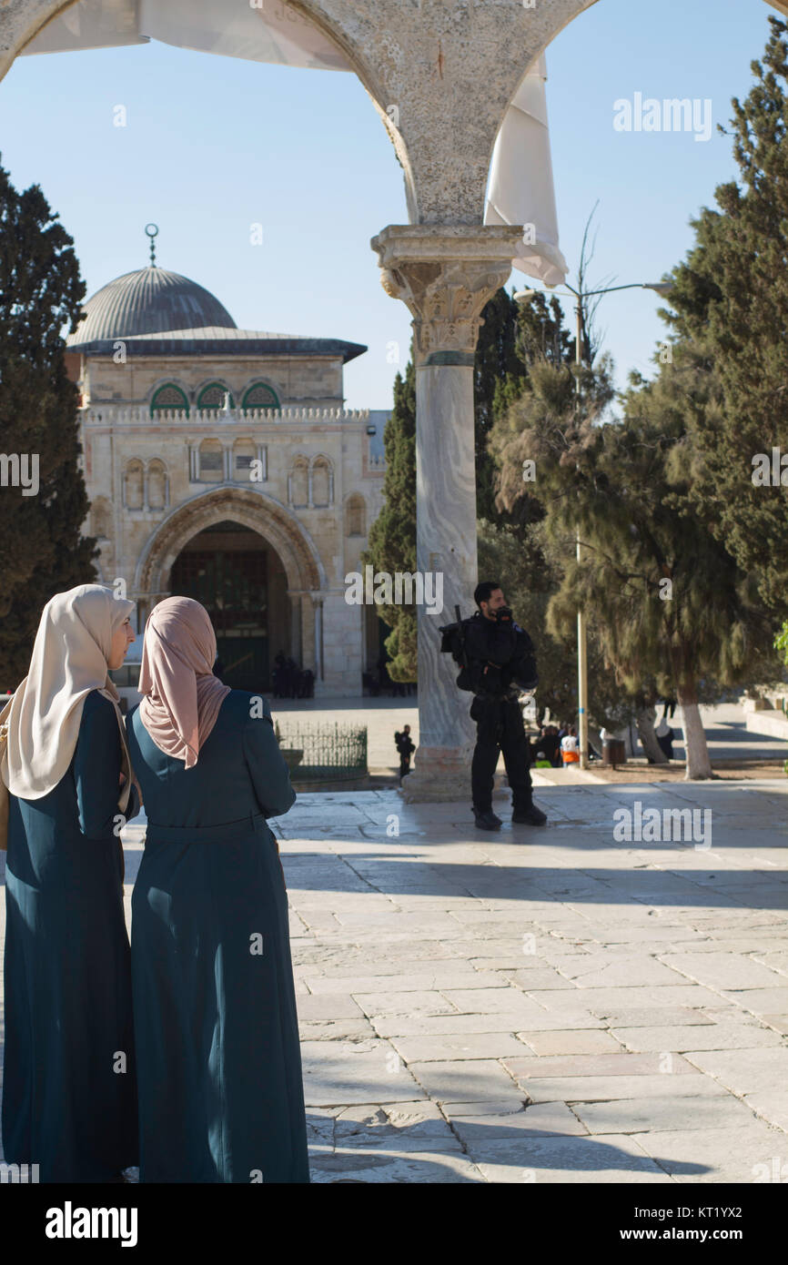 Le donne palestinesi guarda come forze di sicurezza israeliane cordon off al-Aqsa moschea per consentire adoratori ebrei al complesso. Foto Stock