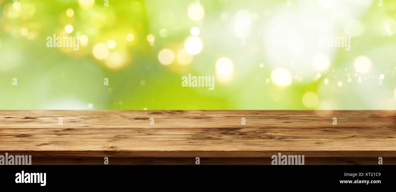 Molla verde con sfondo bokeh di fondo di fronte a un vuoto di tavolo in legno per un concetto Foto Stock