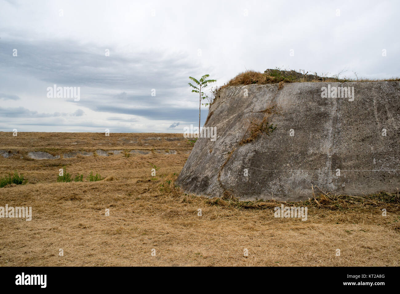 Vista panoramica di un fiume a secco con un vecchio argine irregolare con uno sfondo con cielo nuvoloso nella campagna toscana Foto Stock