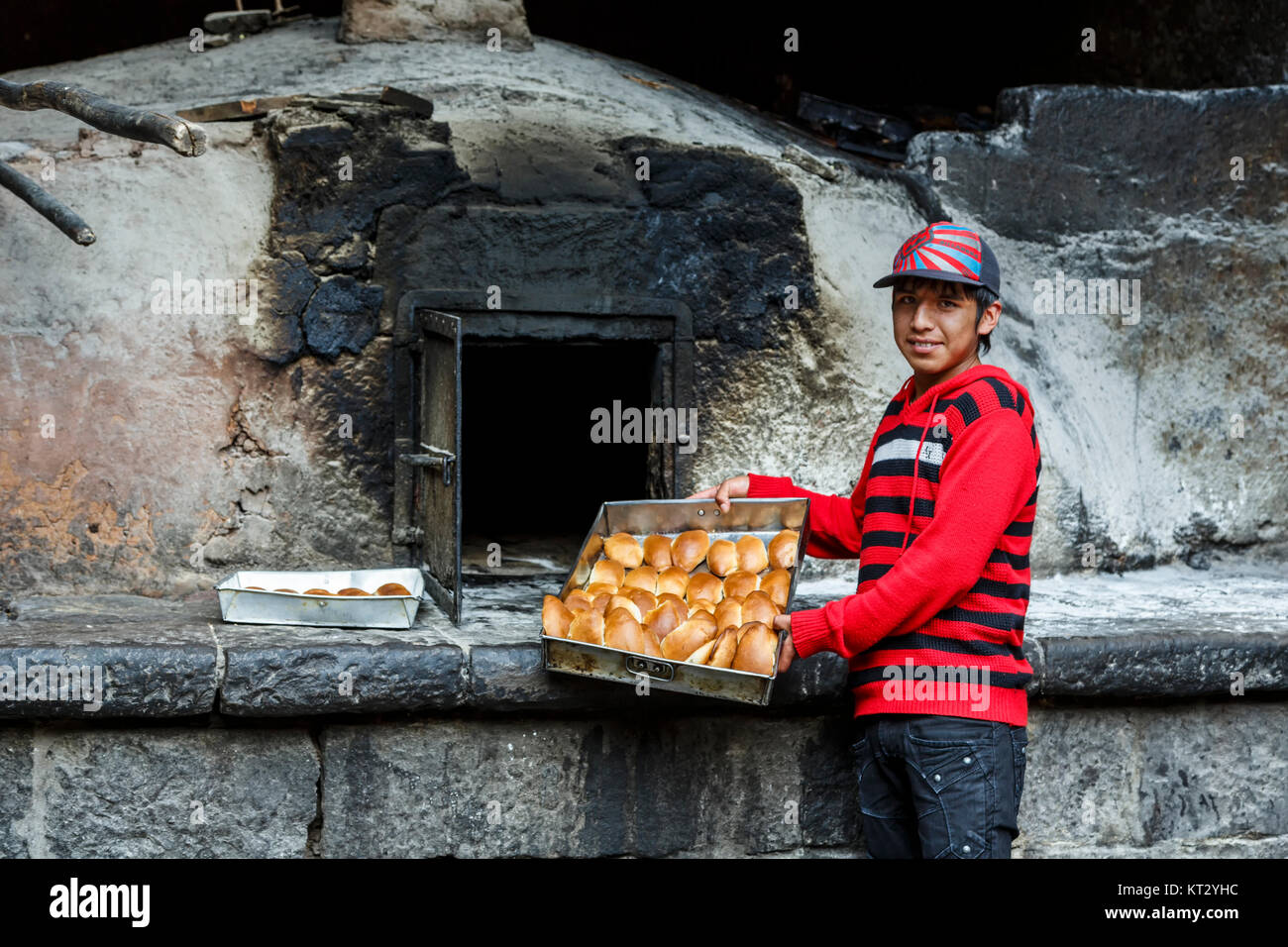 Server maschio con le empanadas di fronte storico coloniale Horno San Francisco (San Francisco forno coloniale), il villaggio di Pisac, Cusco, Perù Foto Stock