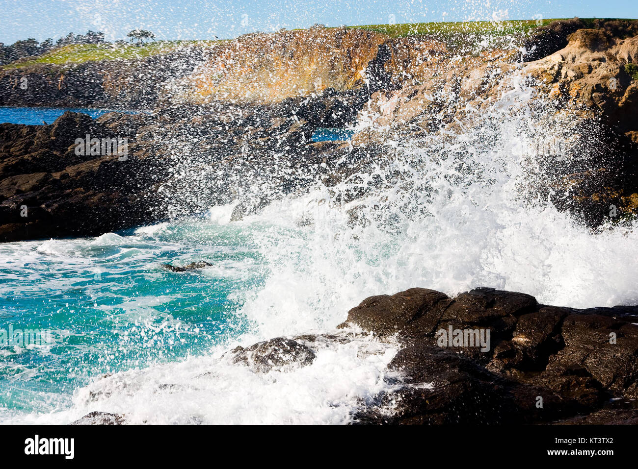 Forme d'onda colpendo costa rocciosa Foto Stock
