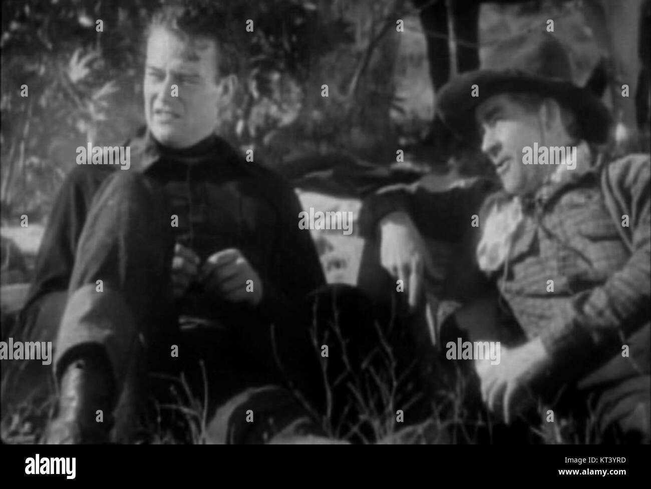 Questa immagine presenta le star di Hollywood John Wayne e George Hayes in una scena da *West of the divide*, un film western del 1934. Il film fa parte del classico genere western per cui John Wayne è diventato famoso. Foto Stock