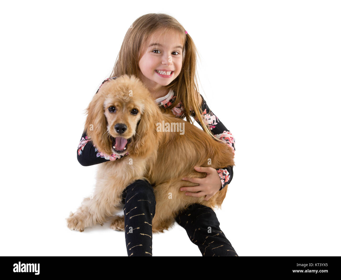 Ragazza giovane grinning presso la telecamera come essa abbraccia il suo cucciolo, un bel po' di golden cocker spaniel, nelle sue braccia su bianco Foto Stock
