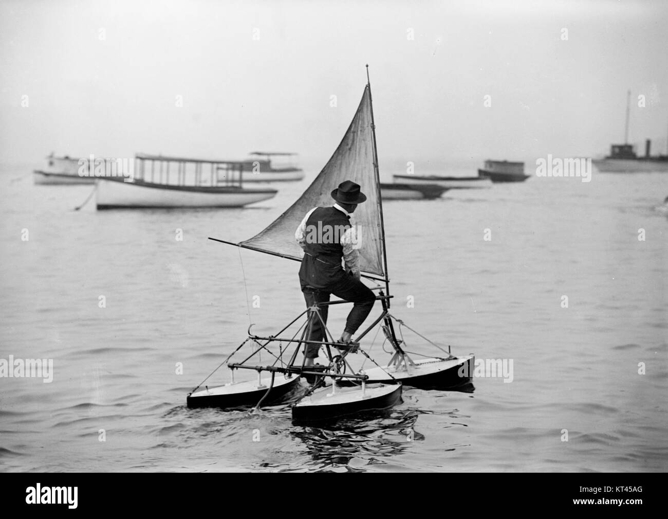 Viene mostrato un uomo che gestisce un triciclo d'acqua, un mezzo di trasporto unico dall'inizio del XX secolo. Questa immagine cattura l'innovazione del tempo e l'uso del trasporto via acqua. Foto Stock