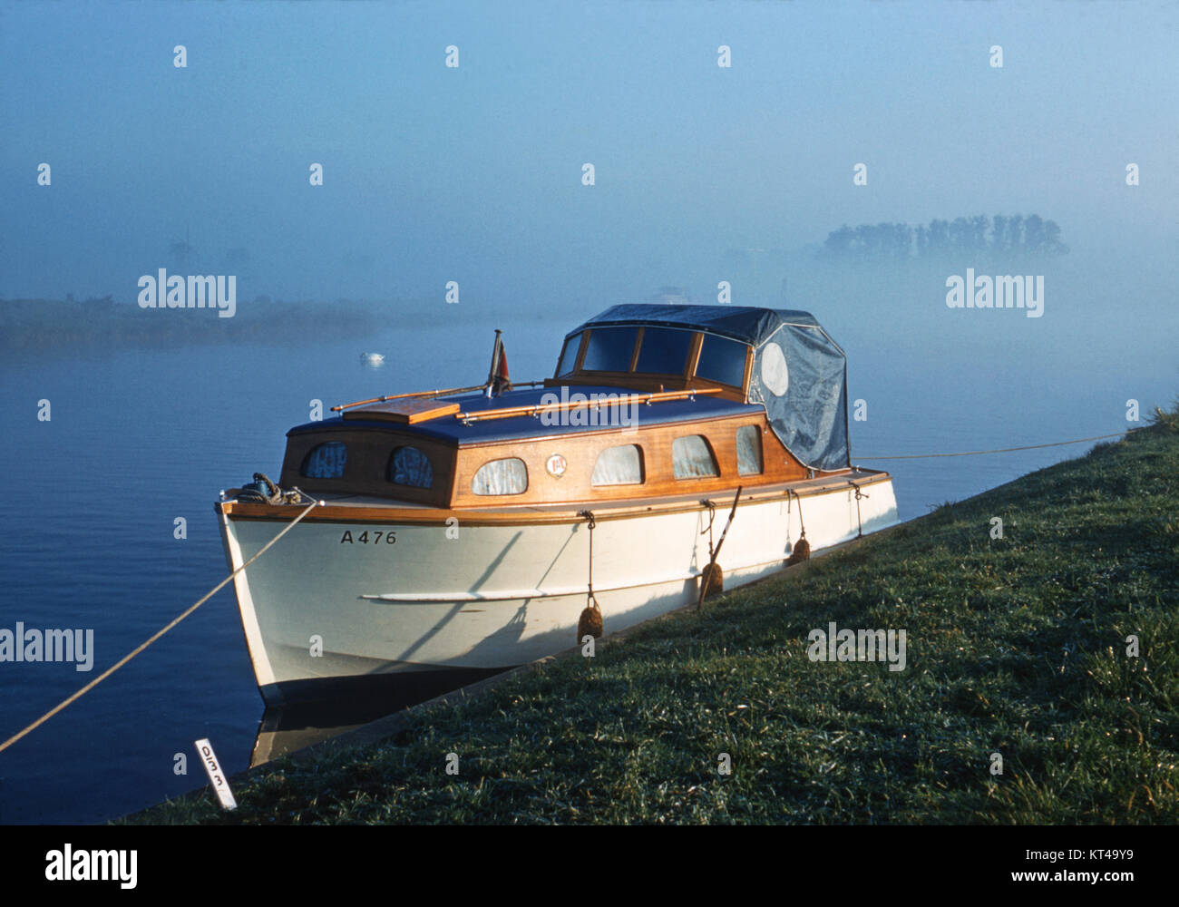 Piccola barca a motore ormeggiata sulla riva del fiume Bure, Norfolk, con early MORNING MIST Foto Stock