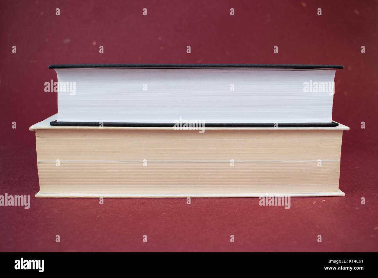 Due libri con copertina rigida su ogni altro su uno sfondo di colore rosso. Il bianco e il nero prenota Foto Stock