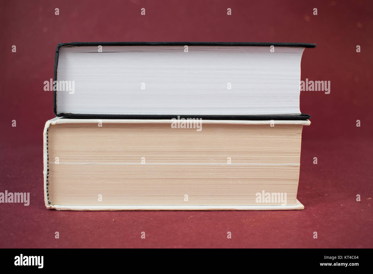 Due libri con copertina rigida su ogni altro su uno sfondo di colore rosso. Il bianco e il nero prenota Foto Stock