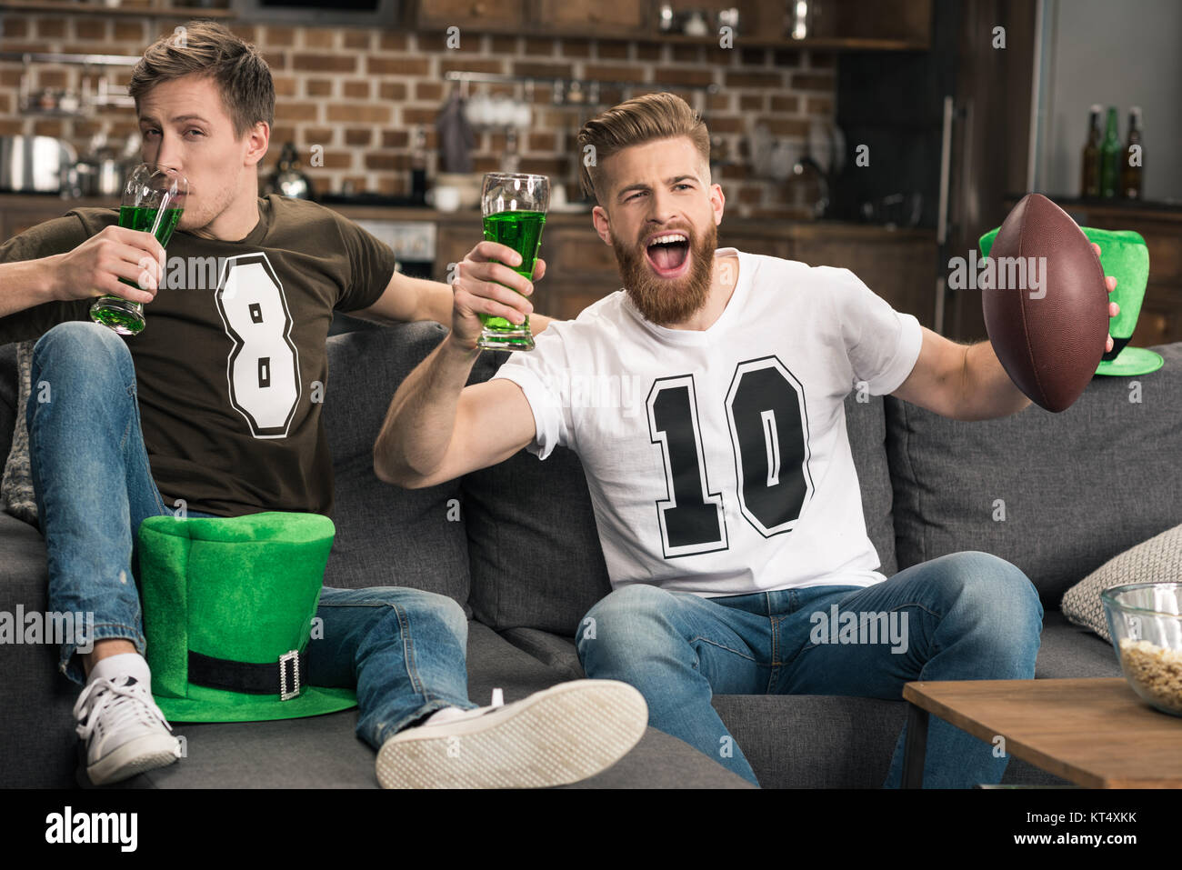 Entusiasti giovani uomini con bicchieri da birra guardando la partita di calcio presso il giorno di San Patrizio Foto Stock