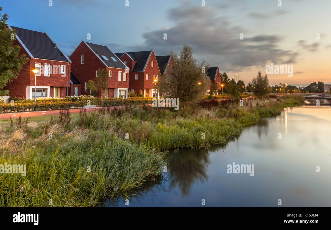 Una lunga esposizione night shot di strada con ecologici moderni middle class case famiglia con eco friendly banca di fiume in Veenendaal città, Paesi Bassi. Foto Stock