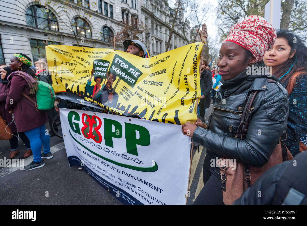 Banner dal Global Afrikan parlamento del popolo in occasione della finale del rally delle persone di marzo per il clima e i posti di lavoro a Londra fare accuse di genocidio e ecocide contro le potenze coloniali. Foto Stock