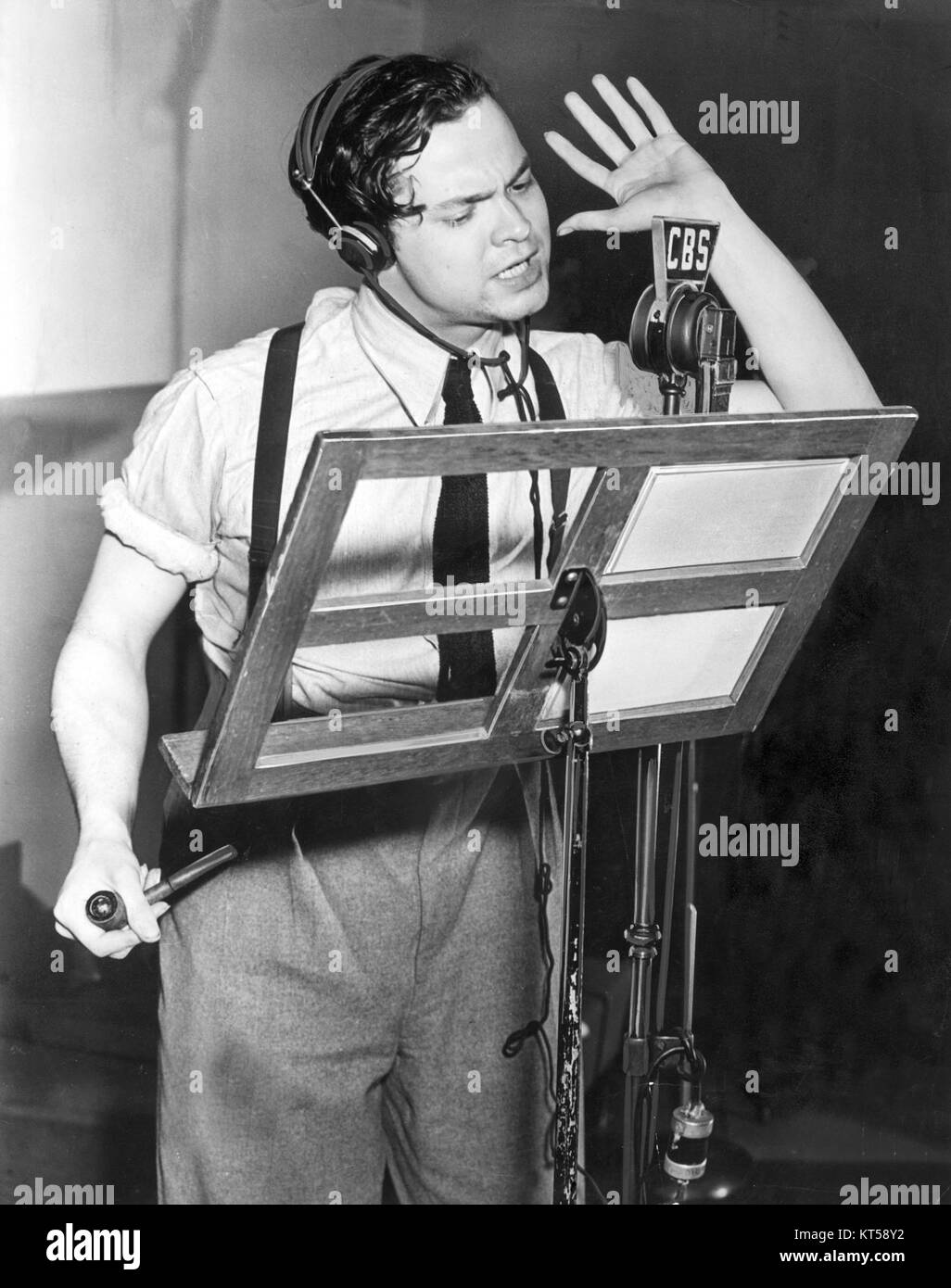 Questa immagine del 1938 mostra Orson Welles nel suo studio, probabilmente durante l'apice della sua carriera radiofonica. Welles era una figura di spicco nell'intrattenimento americano, noto per il suo lavoro in radio, cinema e teatro. Foto Stock