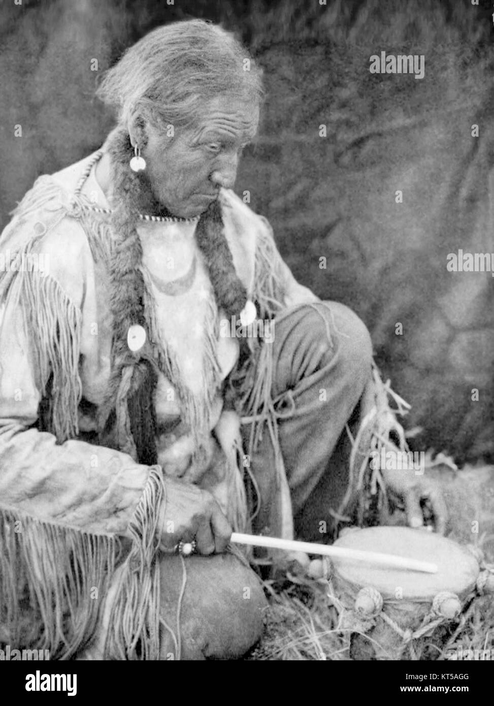 "Peyote Drummer" di Edward S. Curtis cattura il significato spirituale e culturale dei rituali dei nativi americani. L'immagine raffigura un batterista durante una cerimonia Peyote, che simboleggia una parte importante delle tradizioni indigene. Foto Stock