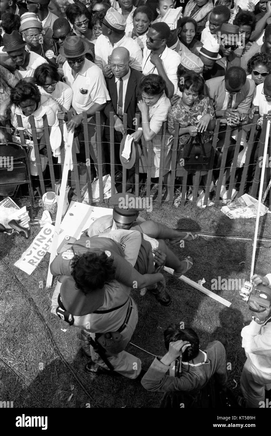 Una potente immagine della marcia su Washington del 1963, che mostra la polizia che trasporta una donna durante un momento significativo nel movimento per i diritti civili, evidenziando le tensioni e l'attivismo dell'epoca. Foto Stock