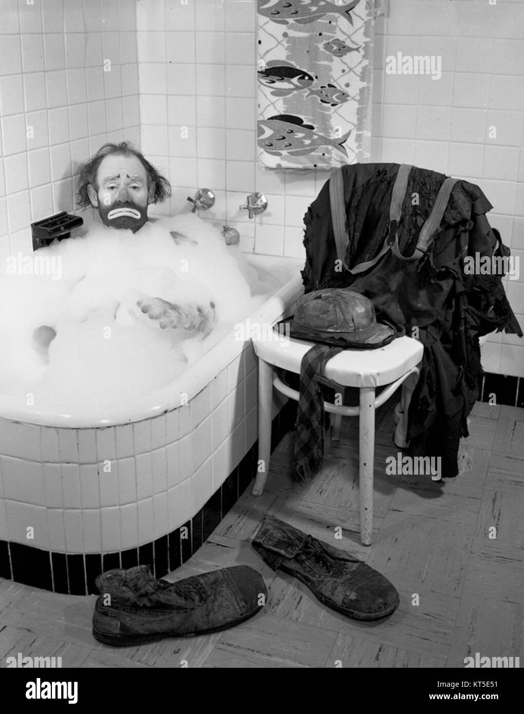 Emmett Kelly, un famoso clown dei Ringling Bros Circus, viene catturato in un momento giocoso facendo un bagno di bolle a Sarasota, Florida, che riflette il lato umoristico e stravagante della vita circense. Foto Stock
