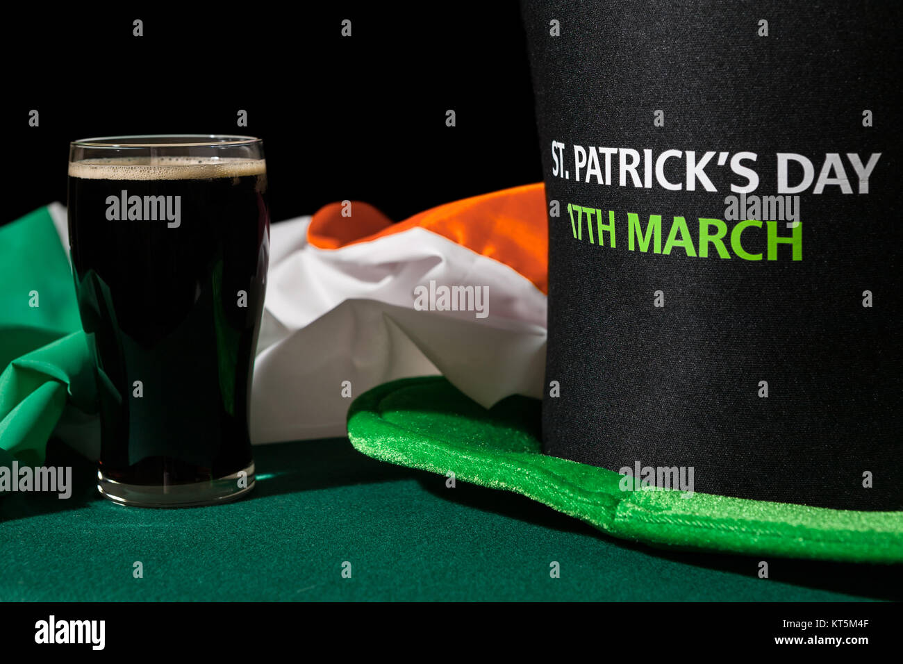 Primo piano di St Patrick giornata con una pinta di birra nera, cappello e bandiera irlandese Foto Stock