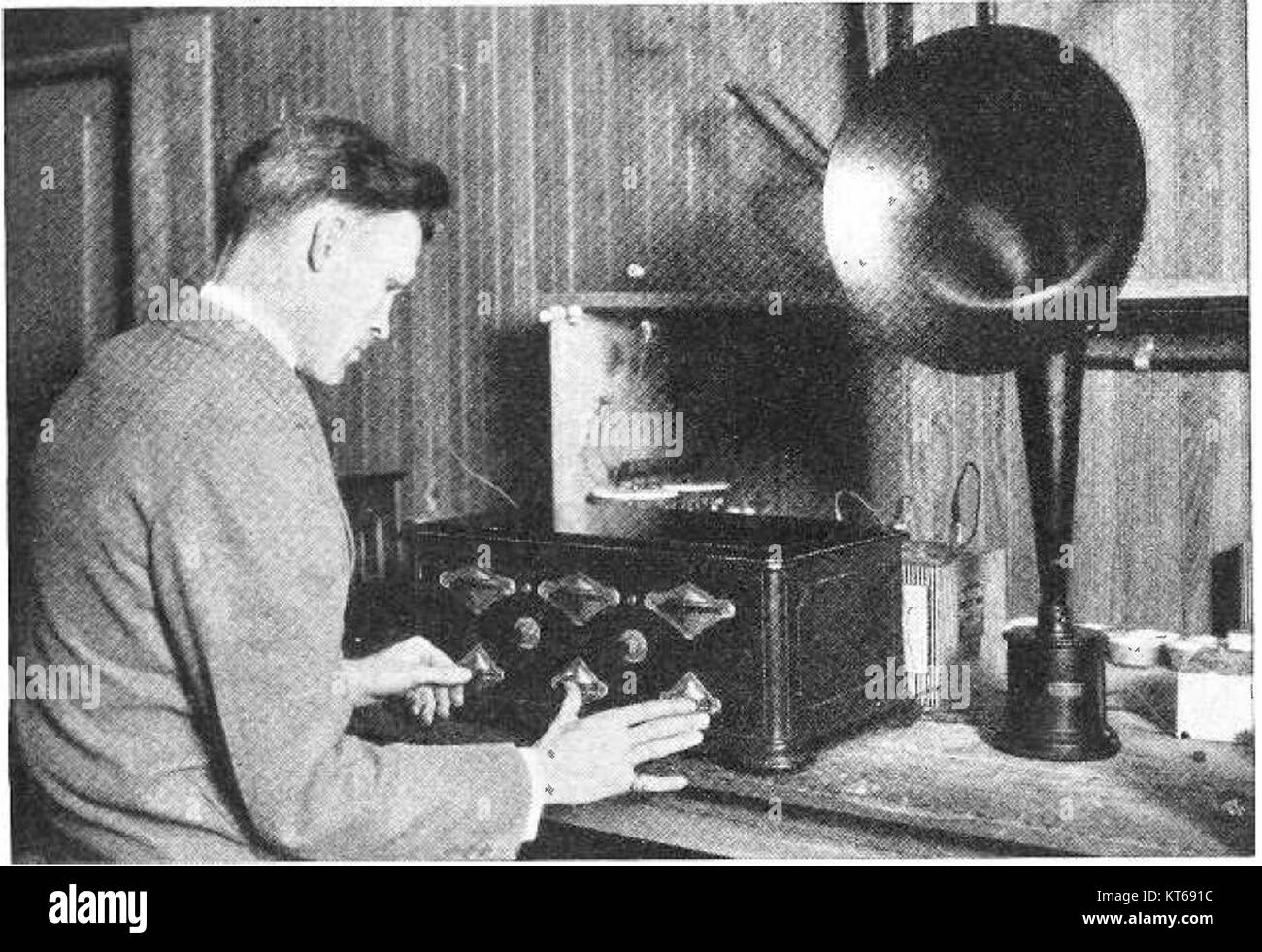 Questa immagine raffigura una persona che sintonizza una radio TRF (TUNED radio Frequency) del 1925, che rappresenta la prima tecnologia radio e il suo ruolo nella comunicazione durante l'inizio del XX secolo. Foto Stock